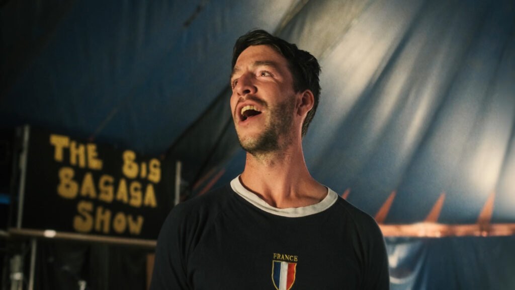 A man singing with a sign behind him containing the text, 'the big bagaga show'